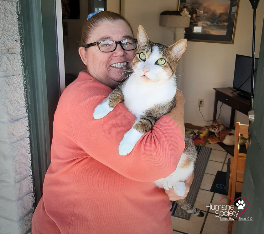 An animeals recipient stands with her cat smiling.